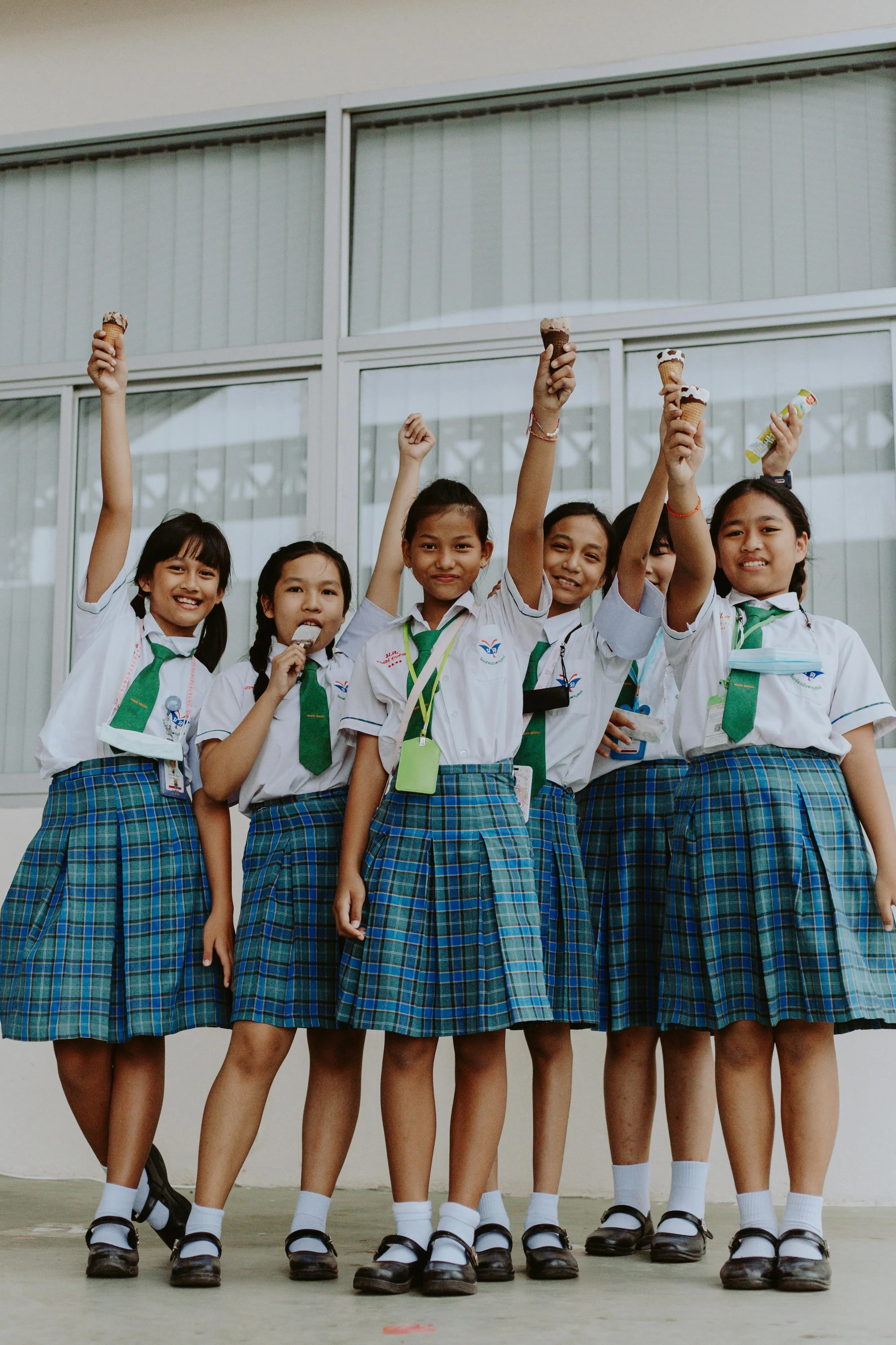 Smiling schoolchildren in uniform enjoying a treat together